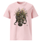 A light pink short-sleeve crewneck t-shirt featuring a Wry Bird graphic print of a vintage gas mask filled with colorful wildflowers, shown against a plain white background.