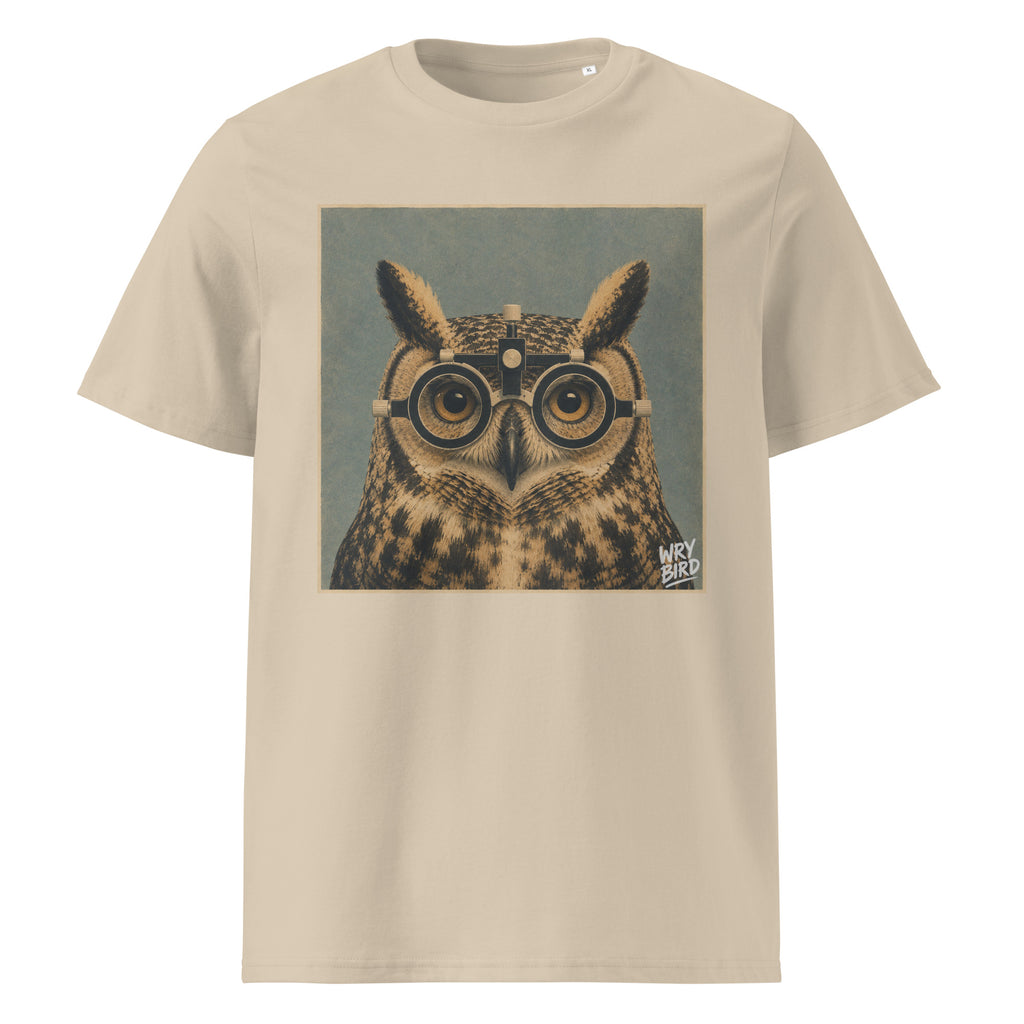 A beige short-sleeve Wry Bird crewneck t-shirt featuring a square graphic print of an owl wearing eye test glasses, set against a muted blue-gray background. 